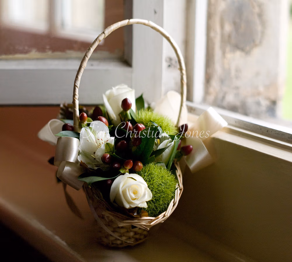 Bridesmaid's flower basket photographed in misty light, placed by a window in a rustic Yorkshire wedding venue