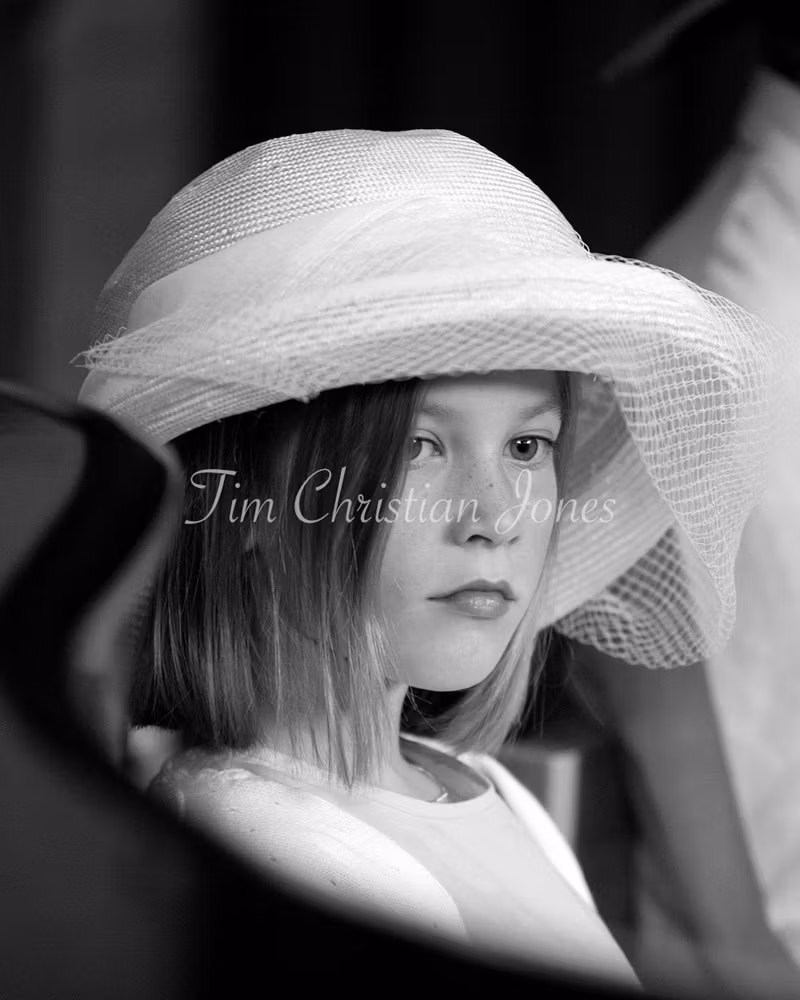 Lovely photo of a young girl in the wedding church pews looking thoughtful 