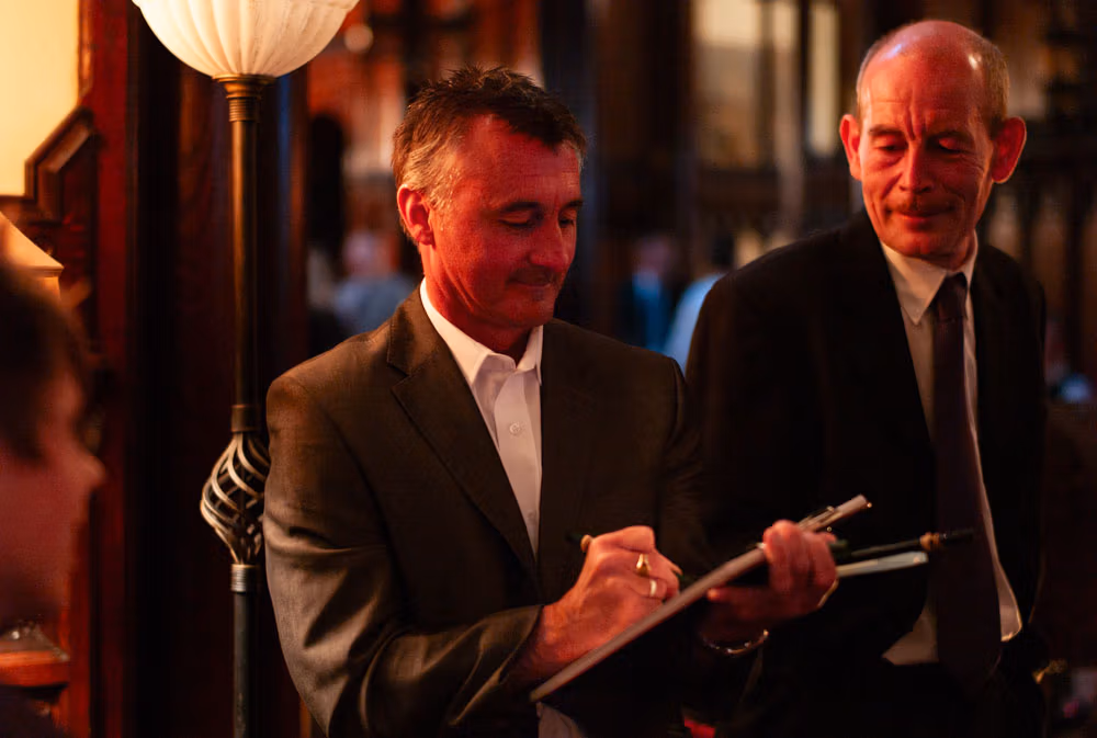 A wedding guest smiles as a caricaturist sketches their portrait during the reception.