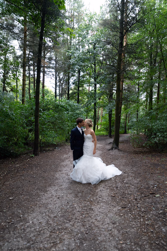 Helen and Adam standing face to face, framed by trees in the Chevin Forest near Chilli Barn