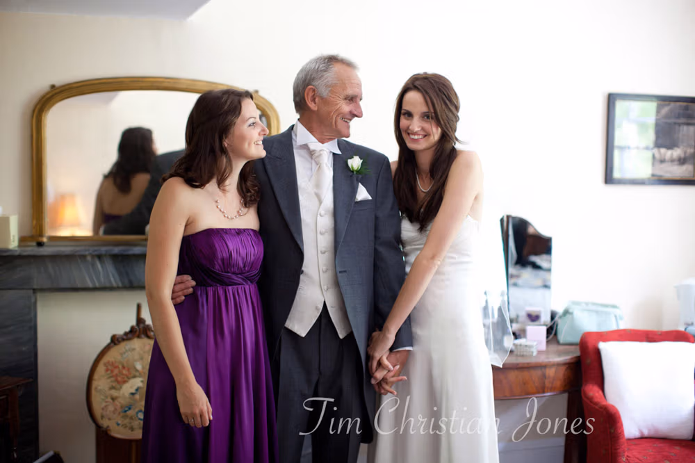Natural moment with Lowri, her sister, and father sharing smiles during the wedding prep

