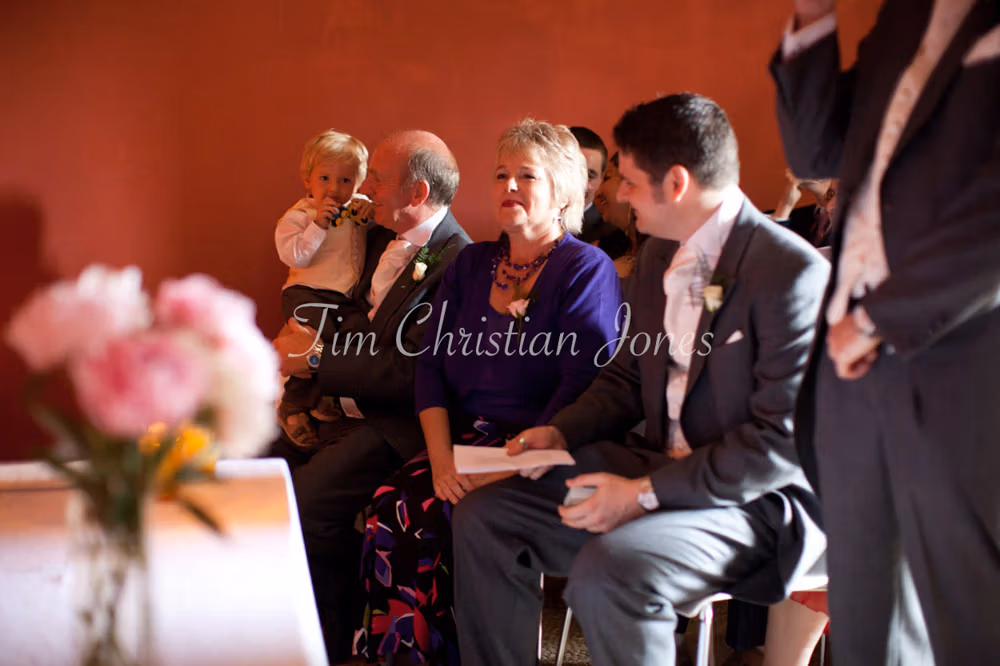 Best man and family members seated in the front row during the wedding ceremony