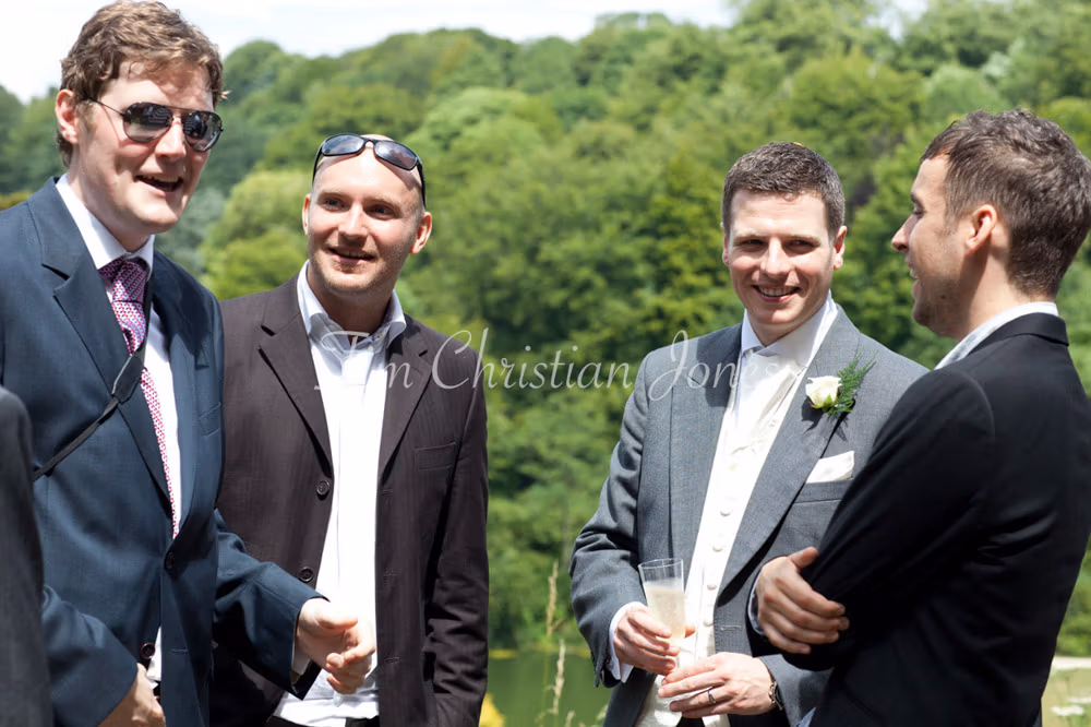 Groom shares a casual moment with three friends at the reception