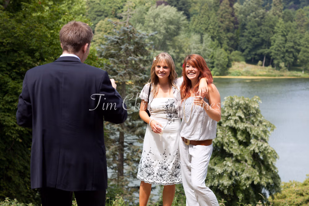 Guests taking photos by the lakeside at a West Yorkshire wedding garden venue