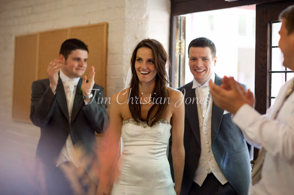 Bride and groom begin their entrance into the reception room, guests inside